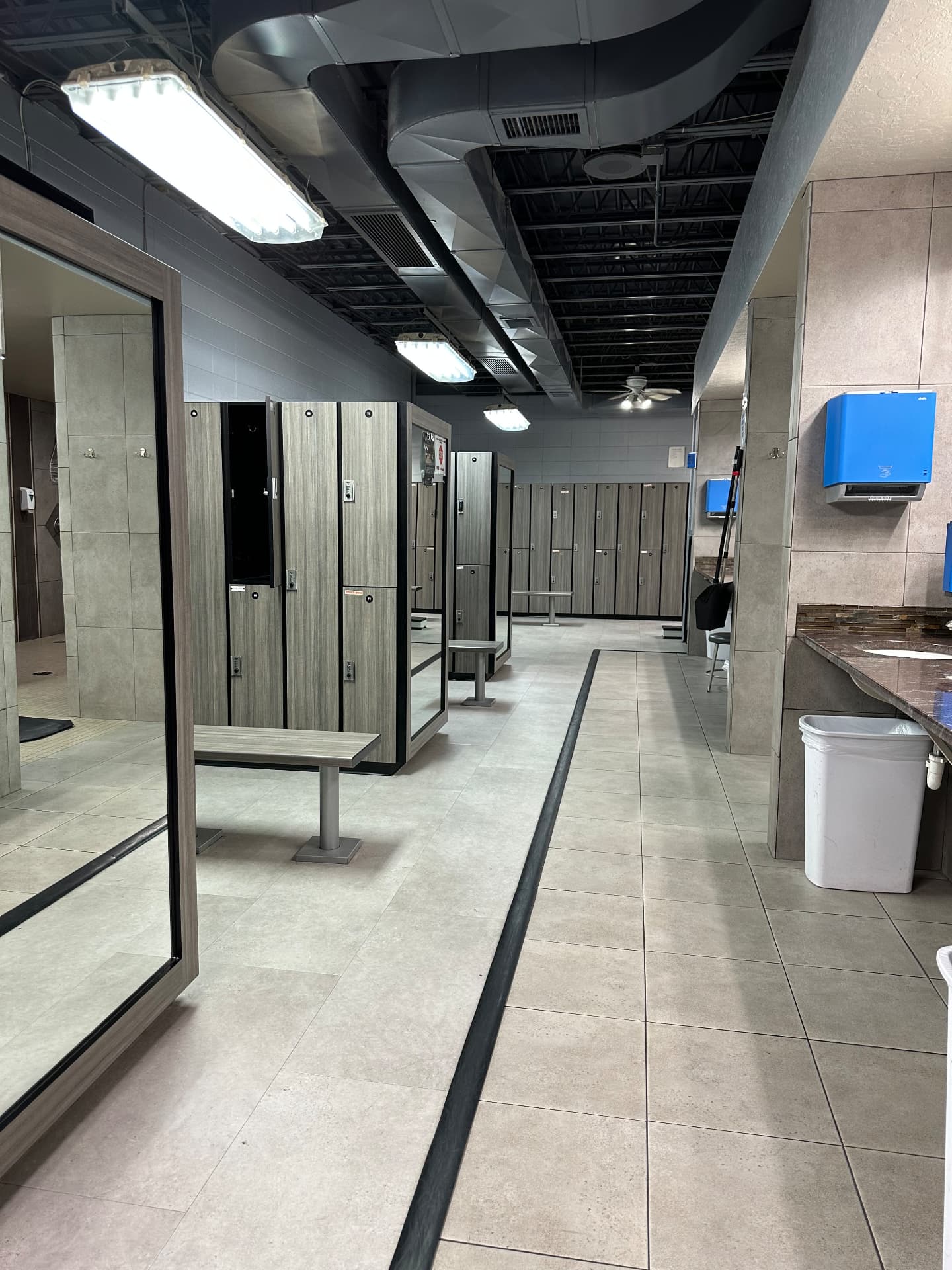Locker room deep clean Gym locker room with mopped tile floors, polished mirrors and restocked dispensers after commercial cleaning