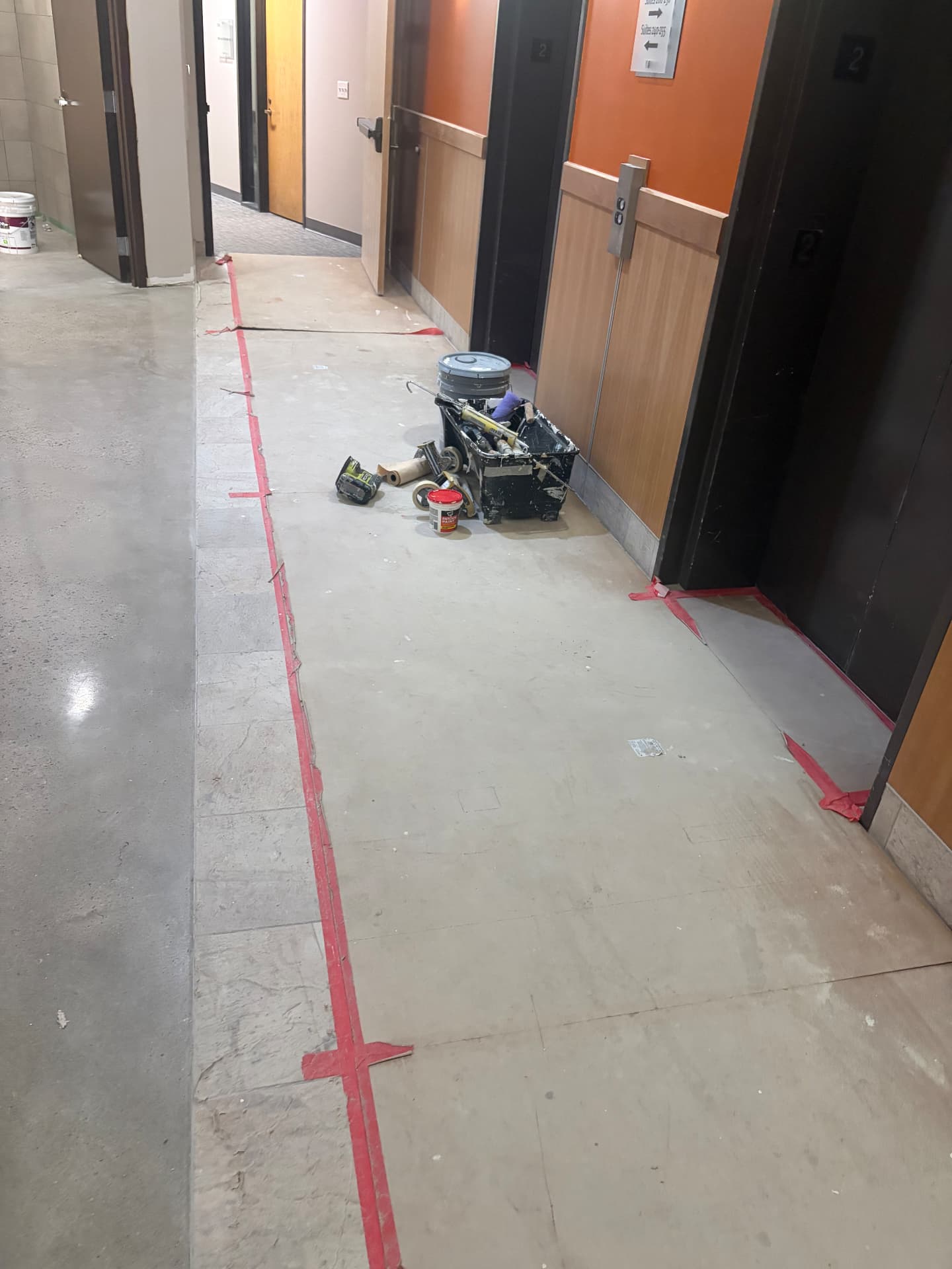 Elevator lobby with protective floor paper and painters' tools during a commercial post-construction cleaning job in Lakewood, CO