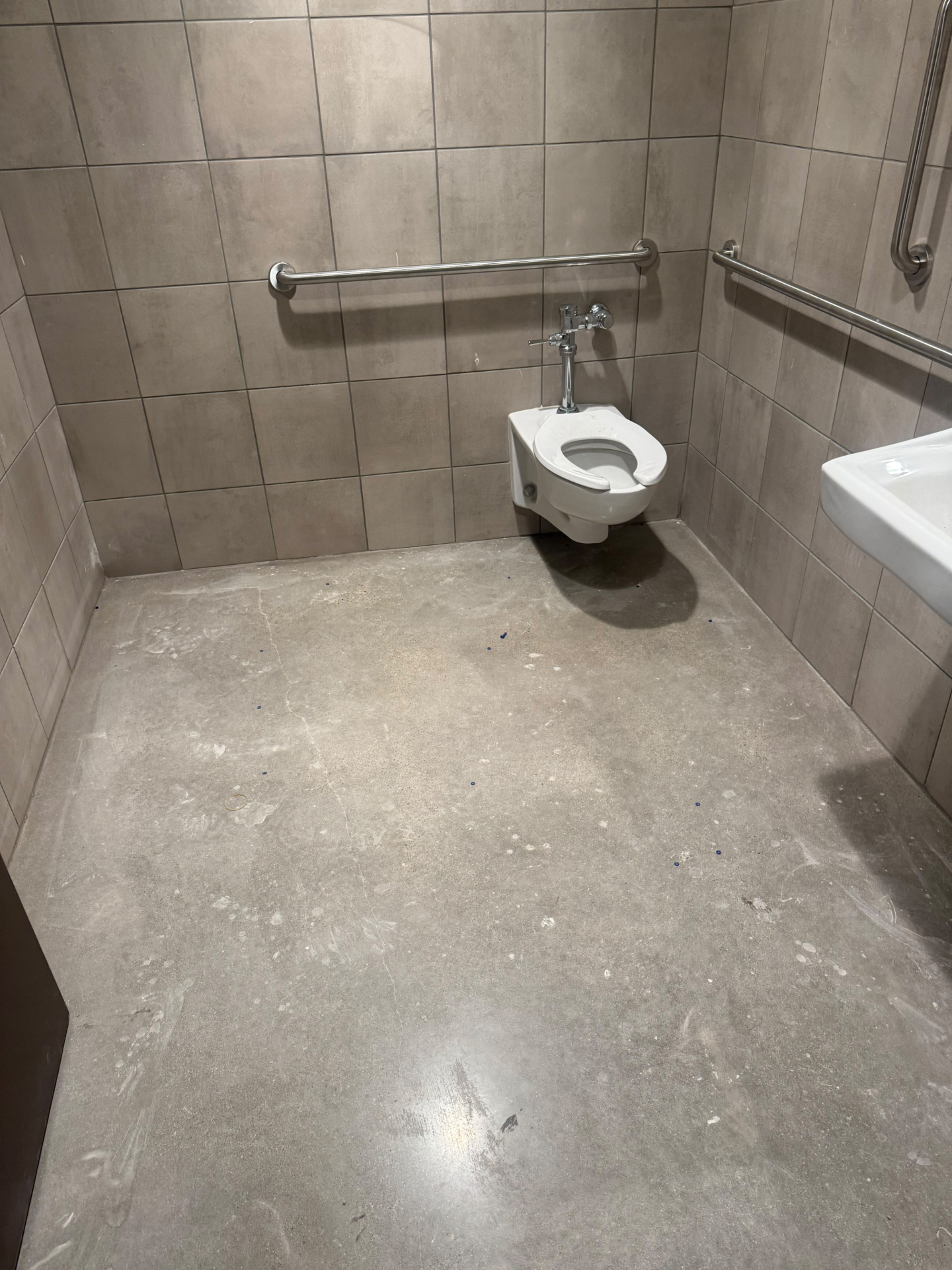 Commercial restroom polished concrete floor and grab bars cleaned after construction