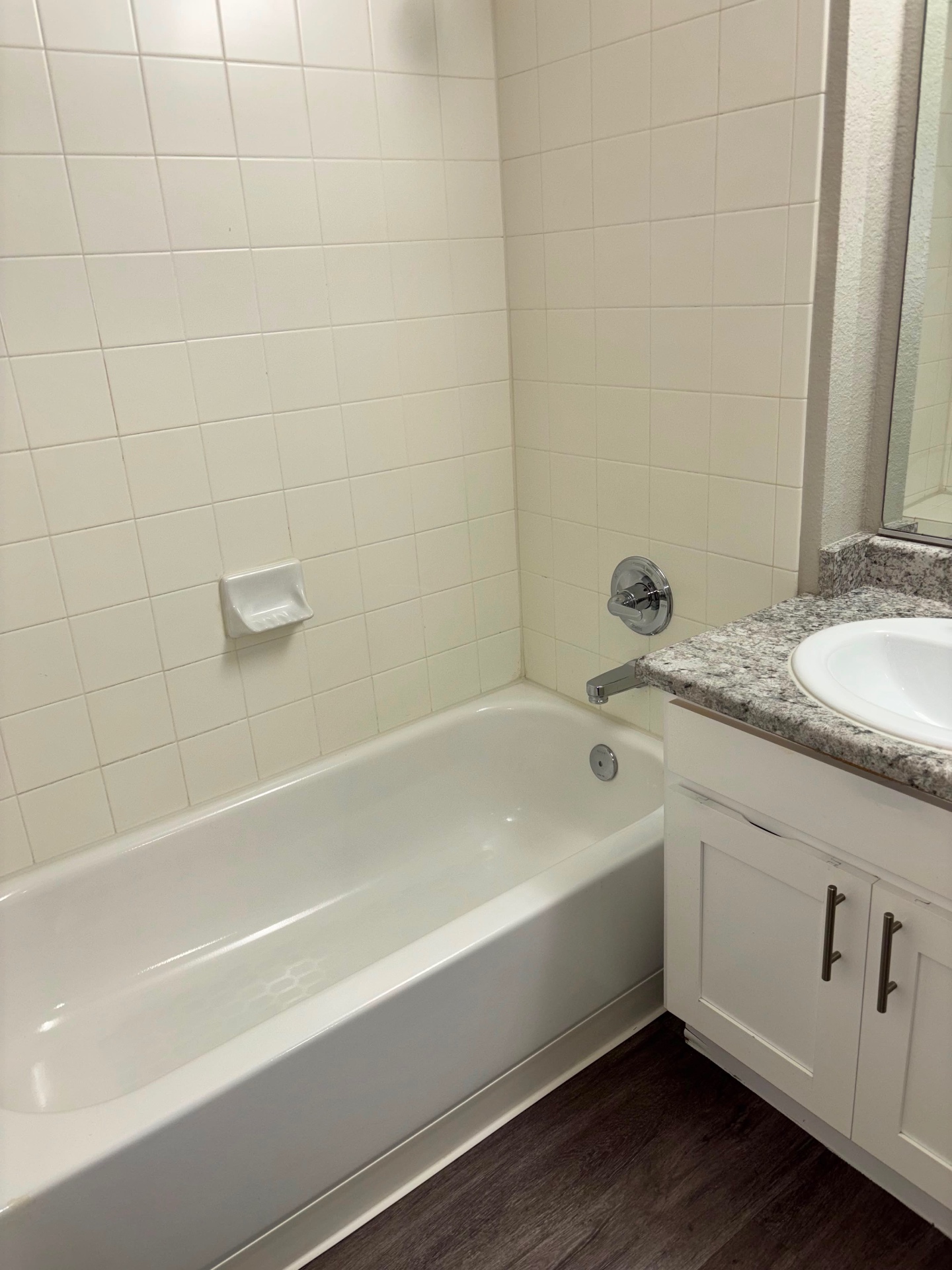 Tiled bathtub, chrome fixtures and granite vanity cleaned in a vacant unit after move-out