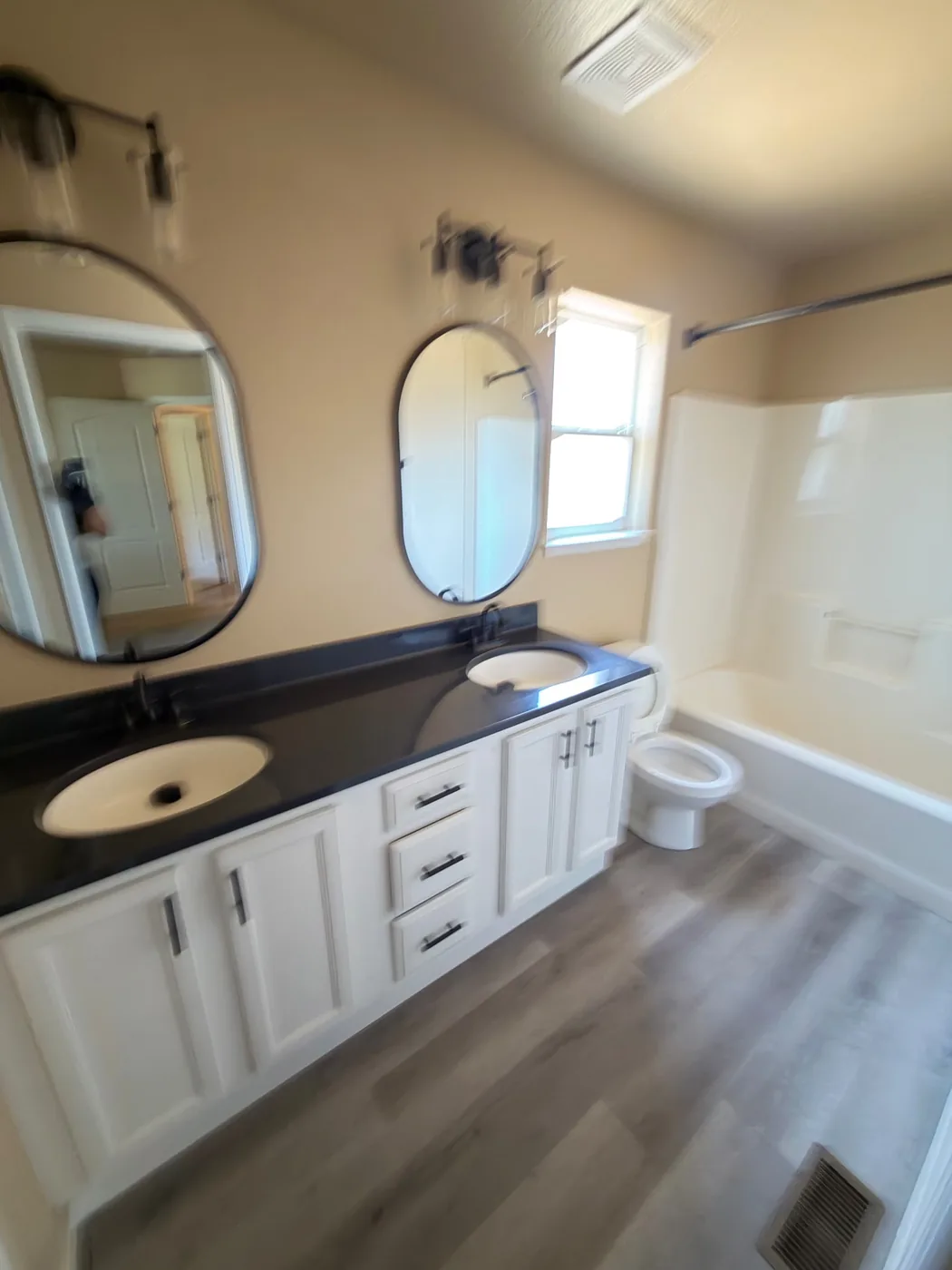 Primary bathroom with two sinks, wood cabinets and a clean tub in a Denver-area home
