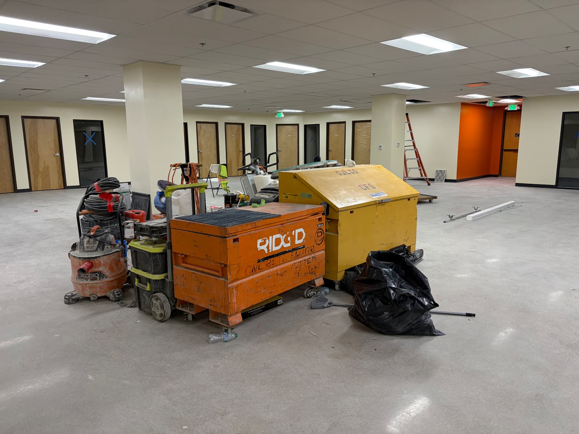 Commercial office build-out during construction with trade tools, job boxes and drywall dust before post-construction cleaning