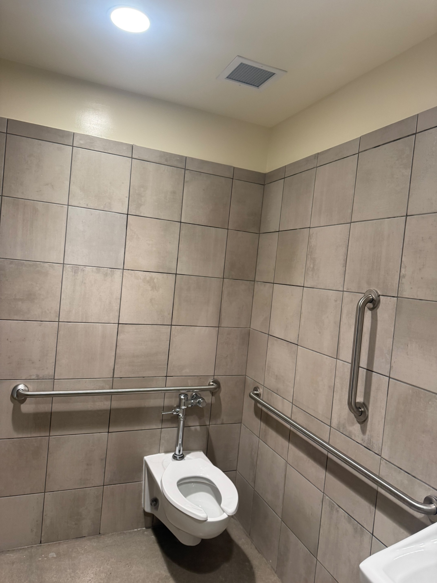 Accessible commercial restroom with tile, grab bars and toilet after a post-construction final clean