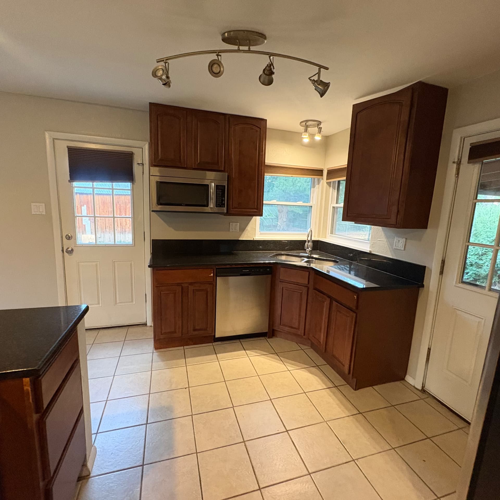Empty kitchen with cherry cabinets and tile floor cleaned during an apartment turnover