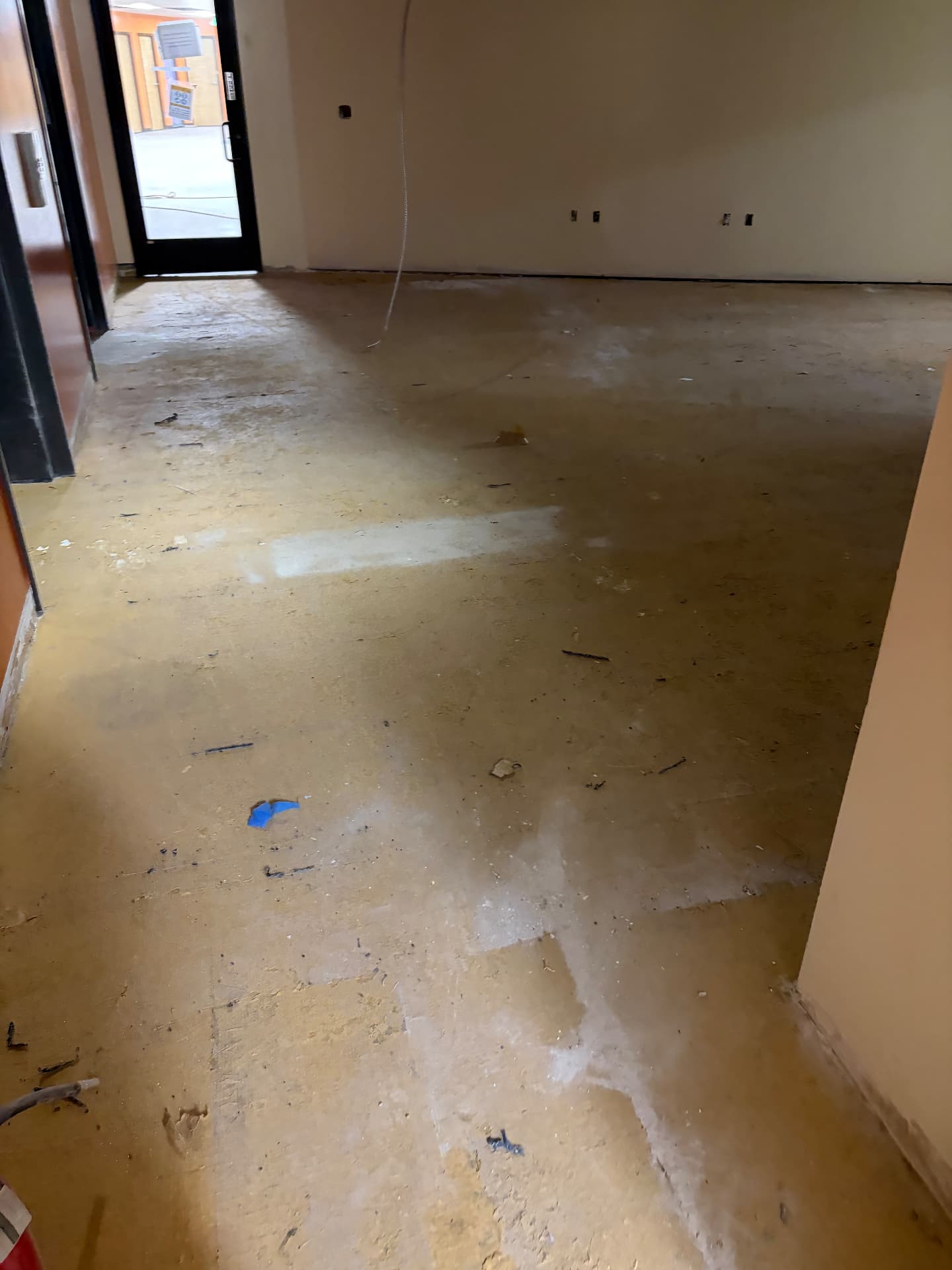 Commercial subfloor covered in adhesive residue and construction dust before a final construction clean