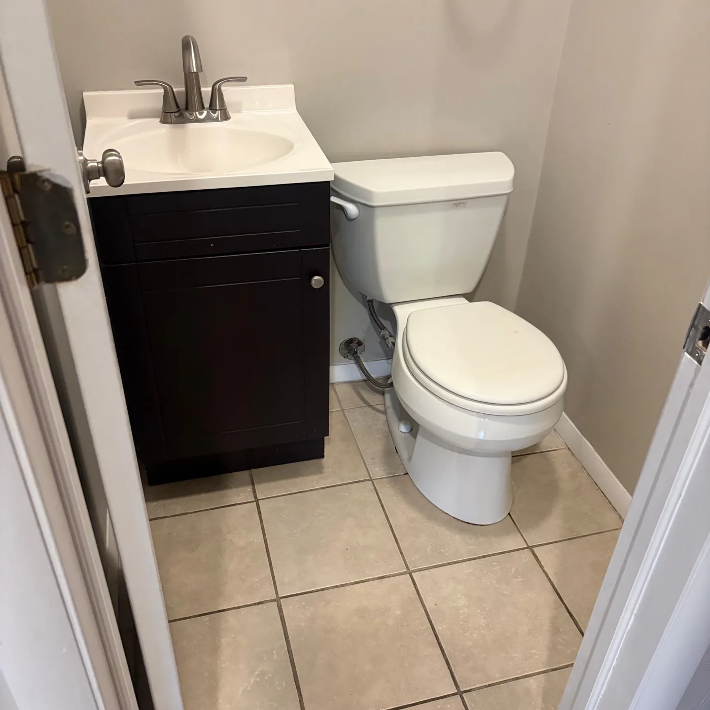 Small half bath with a dark wood vanity and clean tile floor after an apartment turnover