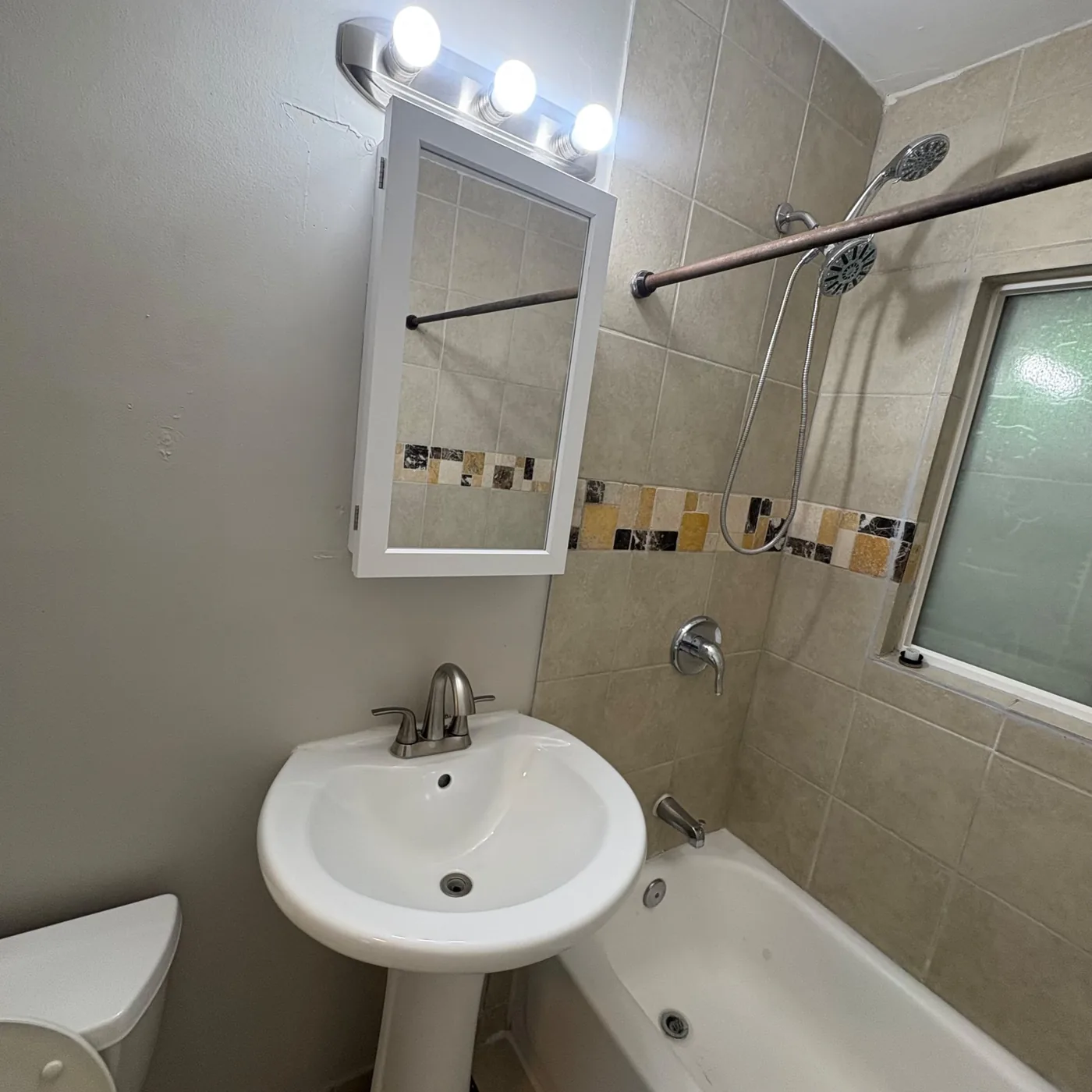 Tiled tub surround and pedestal sink scrubbed clean in a vacant Denver rental bathroom