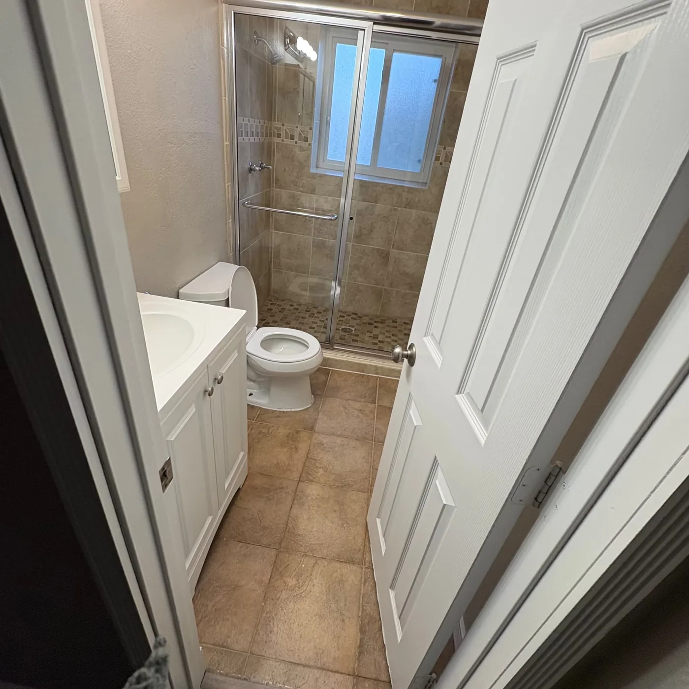 Glass shower stall and white vanity left spotless in a vacant Colorado bathroom