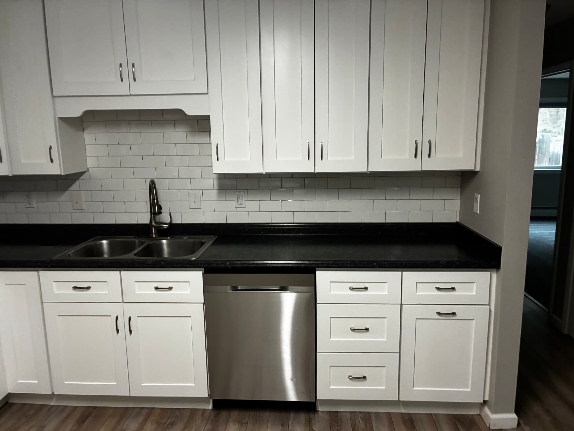 Vacant kitchen with white shaker cabinets, granite counters and subway tile cleaned during a move-out cleaning