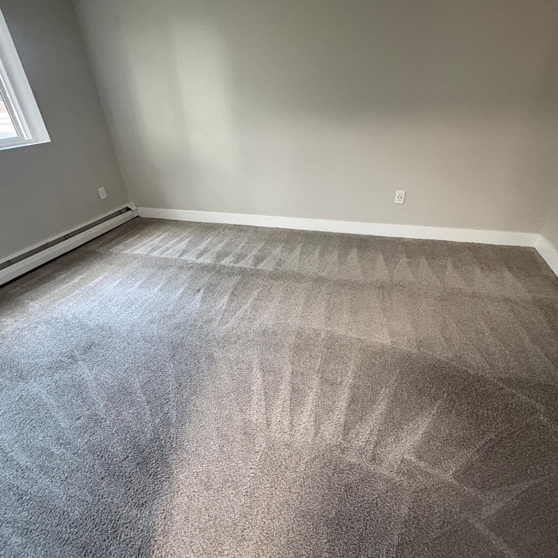 Bedroom carpet cleaned along baseboards and heater during a residential carpet cleaning